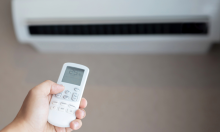 Aire Acondicionado en la pared y una mano que apunta con el control remoto para encerderlo Aires Acondicionados Inteligentes