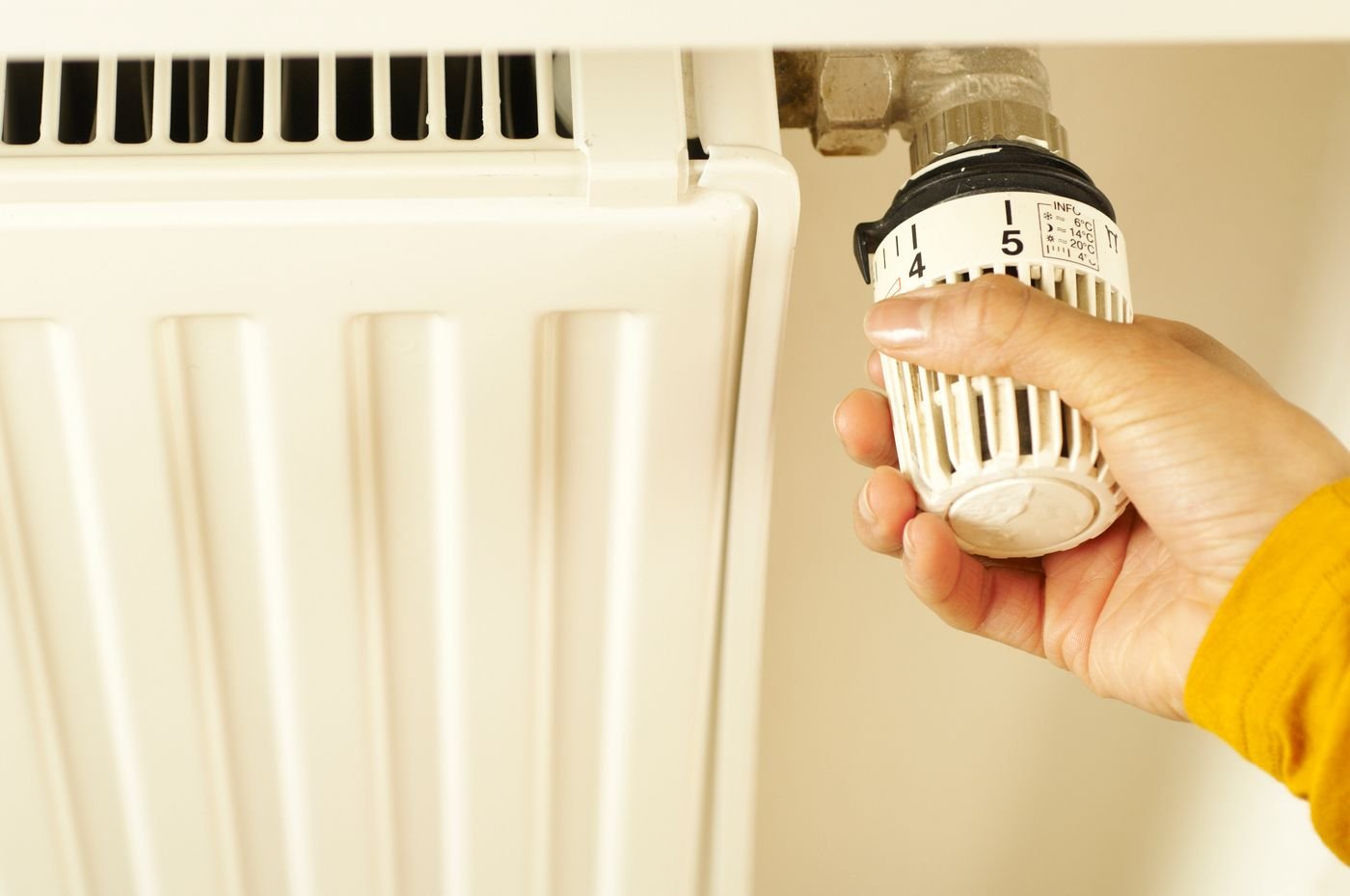 Termostato inteligente 2026: cuánto ahorras de verdad y cuál elegir 2 Mano regulando el cabezal termostático de un radiador antes de instalar un termostato inteligente