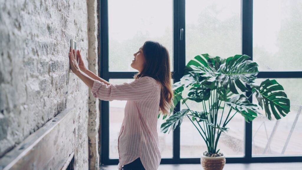 Mujer ajustando un termostato inteligente en la pared del salón de su casa