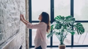 Termostato inteligente 2026: cuánto ahorras de verdad y cuál elegir 2 Mujer ajustando un termostato inteligente en la pared del salón de su casa