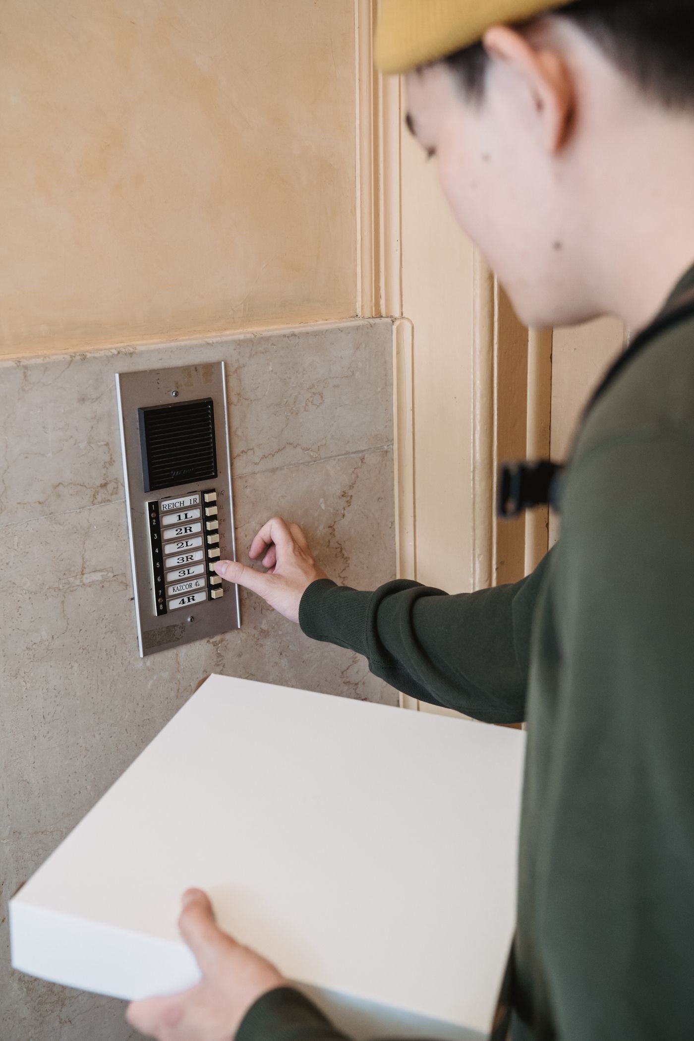Videoportero wifi: cuál comprar según viva en piso o en casa 2 Repartidor con un paquete llamando al portero automático de una comunidad de vecinos